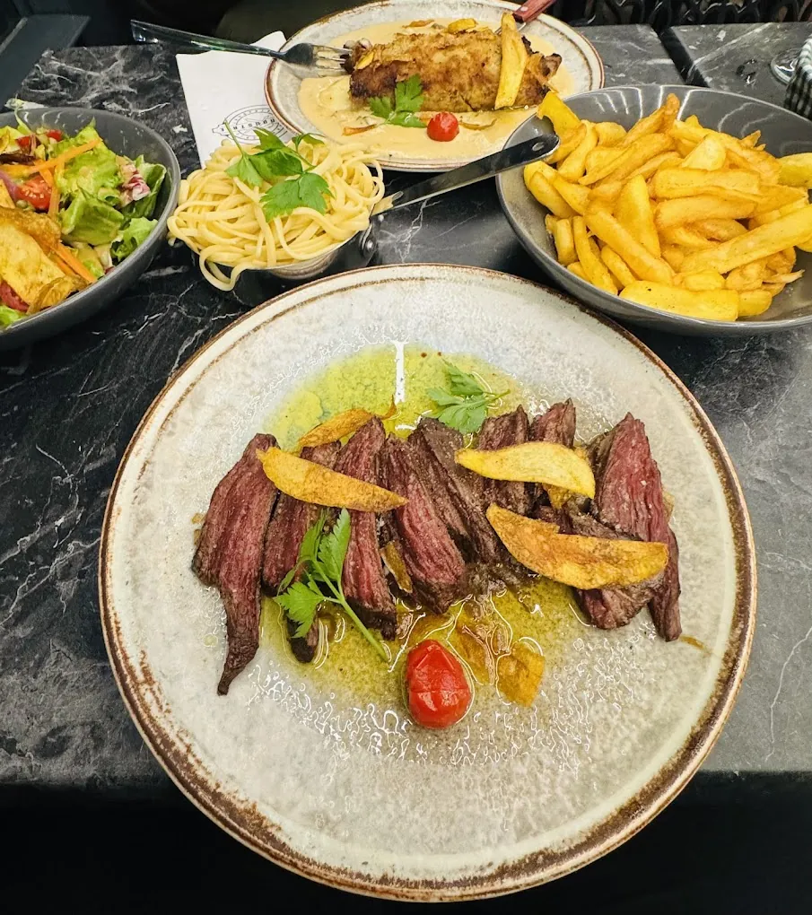 Pièce de bœuf tranchée, frites et pâtes sur la table
